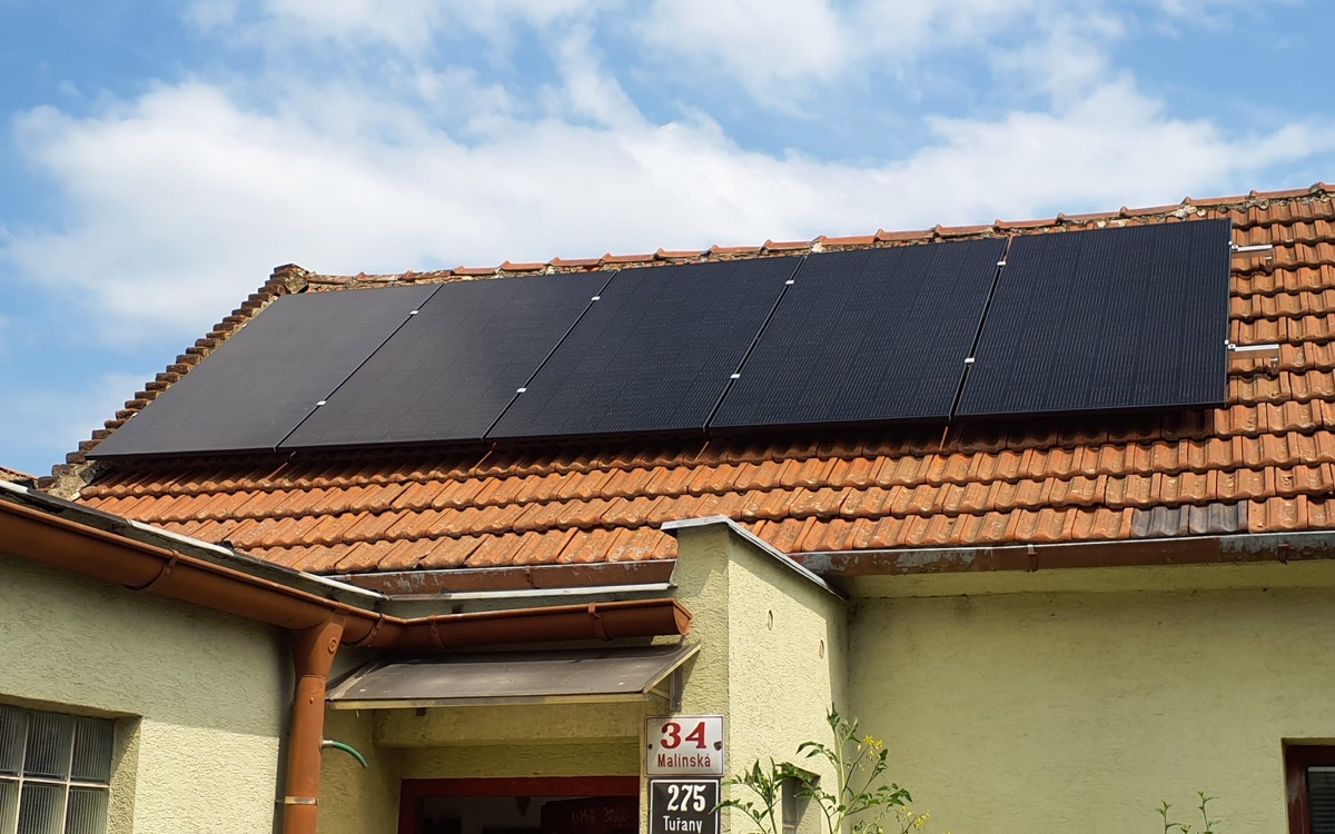 Černé fotovoltaické panely na střeše rodinného domu